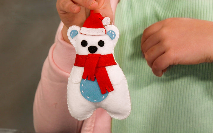 A picture of a completed polar bear ornament with a cute Santa hat and scarf.