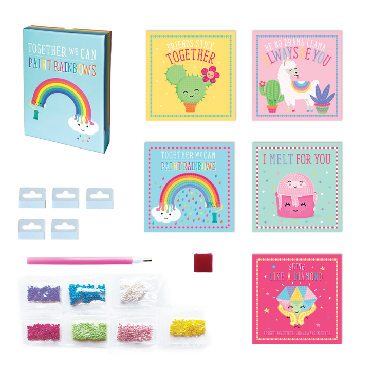 Image of contents of Totally Deco! Diamond Art Set 5 artboard cards with 5 hangers, 7 small bags of assorted  plastic diamond stones, 1 stone pick pen tool, 1 square of pen wax  and instructions, all in a sparkling keepsake storage box made from recycled cardboard.