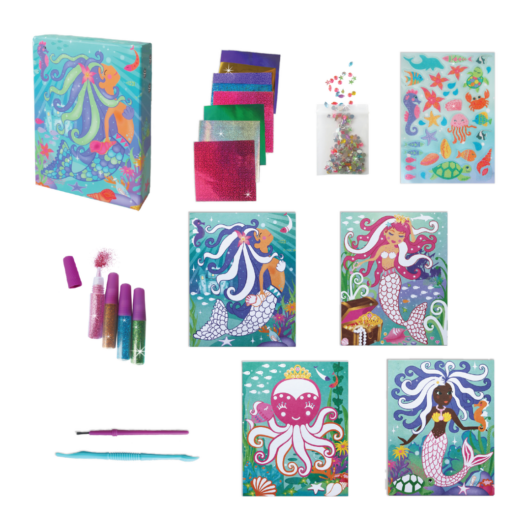 Out of box image of the materials in the Mermaids Glitter & Foil Art Set which Includes: 4 tubes with powder glitter, 1 glitter sticker sheet, 1 plastic brush, 1 plastic craft stick, 8 foil sheets, 4 artboard cards with peel-off paper, 1 bag with assorted plastic gems and instructions, all in a beautiful keepsake storage box made from recycled cardboard.