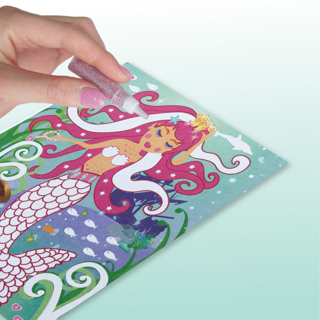 Lifestyle image of a person adding glitter to the mermaids hair.