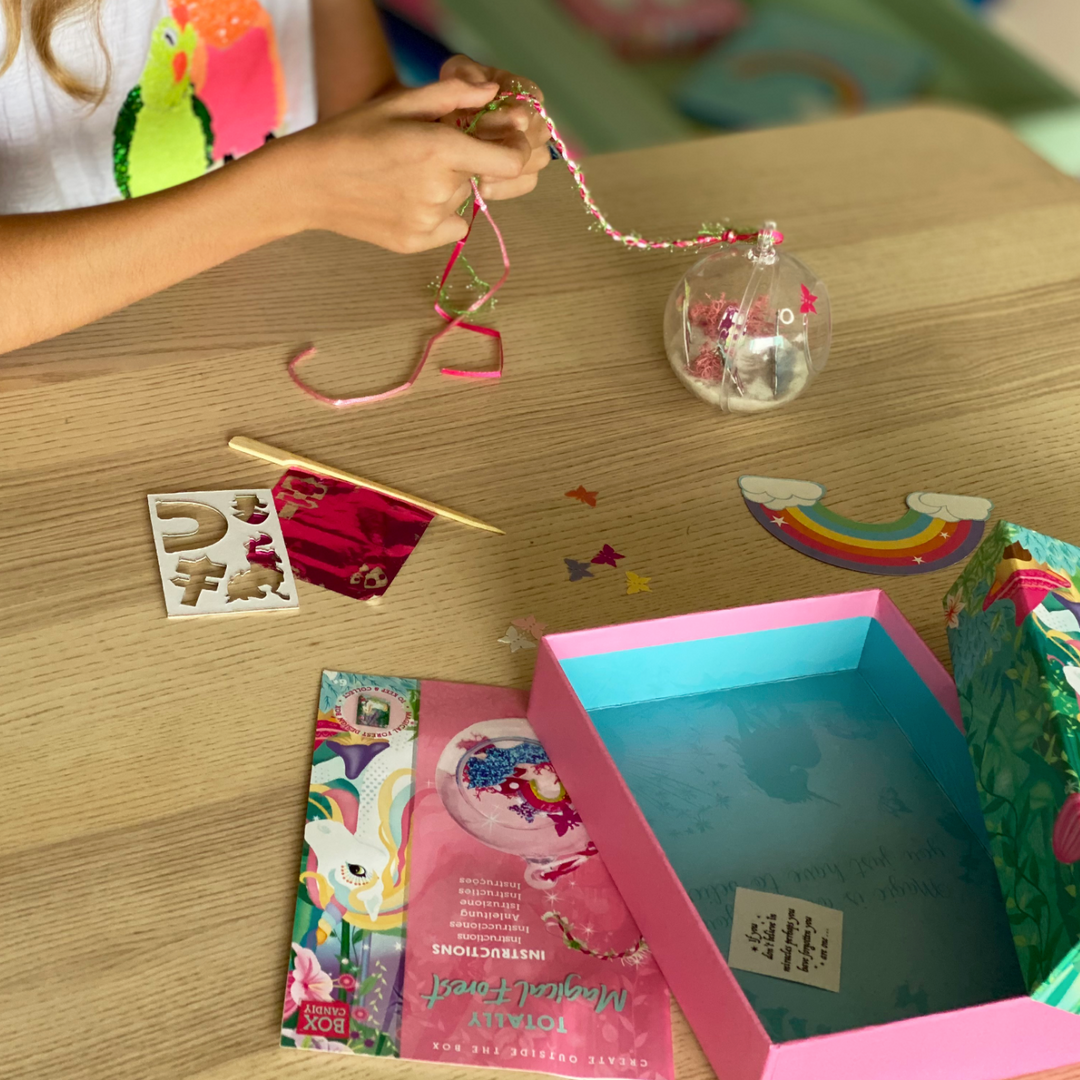 Lifestyle image of a child braiding the string that goes on the Unicorn Terrarium so that it can hang up. 