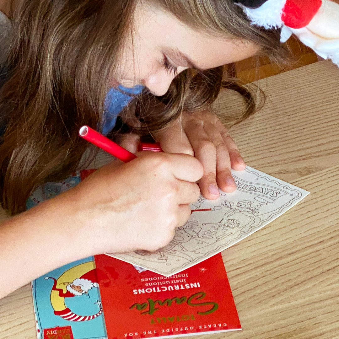 Lifestyle image of a child using the markers to decorate a holiday postcard. 