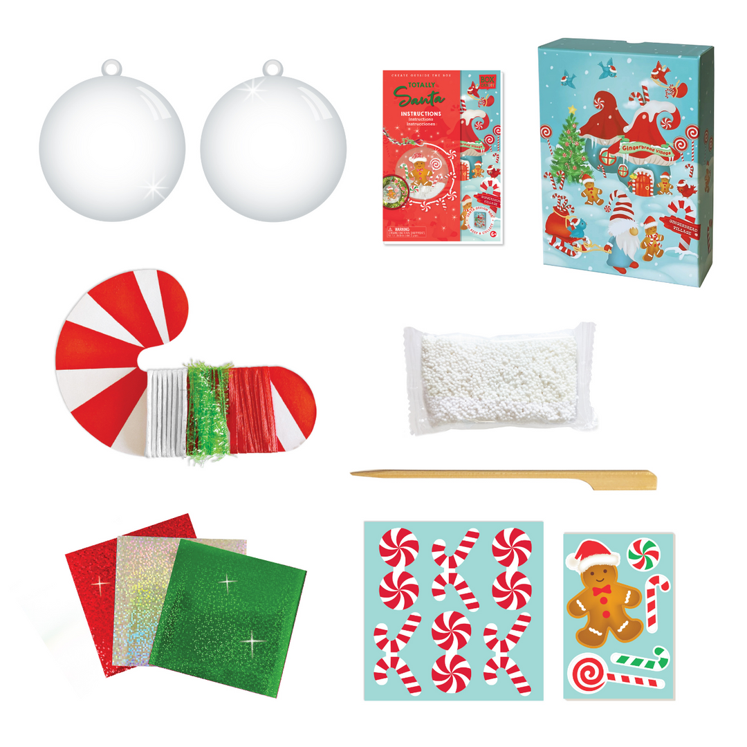 Image of the materials which Includes: 1 (3.5 inch) clear ornament ball, white play foam “snow”, cardboard press out figures, decorative candy cane roll with 3 assorted ribbons and strings, 1 wooden craft stick, 3 colored foil sheets, glitter stickers and instructions, all in a beautiful keepsake storage box made from recycled cardboard.