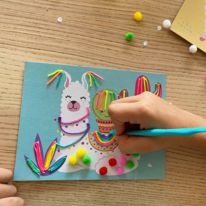 Lifestyle image of a person decorating a Llama in the totally deco String and Pompoms Art Set. 