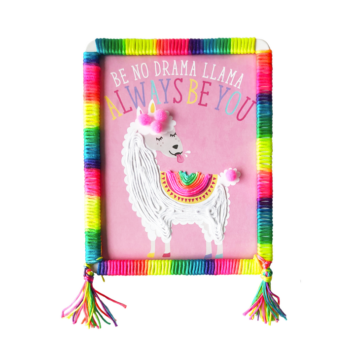 Lifestyle image of a completed Llama Totally Deco String and Pompoms Art that has rainbow string.