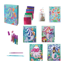 Load image into Gallery viewer, Out of box image of the materials in the Mermaids Glitter &amp; Foil Art Set which Includes: 4 tubes with powder glitter, 1 glitter sticker sheet, 1 plastic brush, 1 plastic craft stick, 8 foil sheets, 4 artboard cards with peel-off paper, 1 bag with assorted plastic gems and instructions, all in a beautiful keepsake storage box made from recycled cardboard.
