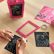 Load image into Gallery viewer, Lifestyle image of a child scratching on a unicorn lantern scratch art set. 

